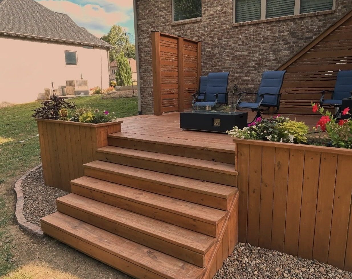 Stained wood deck with wide stairs, built-in planter boxes, a privacy screen, and a fire table.
